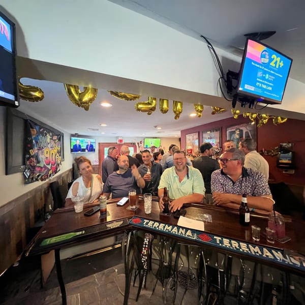 Patrons enjoying drinks and conversation at a lively bar inside The Pieman Pizza restaurant.